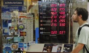 A man walks past a board showing the Real-U.S. dollar exchange rates in Rio de Janeiro March 4, 2015.  REUTERS/Sergio Moraes