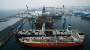 Liquefied petroleum gas (LPG) tankers, front, and a drill rig stand under construction in this aerial photograph taken above the Hyundai Heavy Industries Co. shipyard in Ulsan, South Korea, on Wednesday, July 29, 2015. Hyundai Heavy is one of South Korea's Big Three shipbuilders. Photographer: SeongJoon Cho/Bloomberg